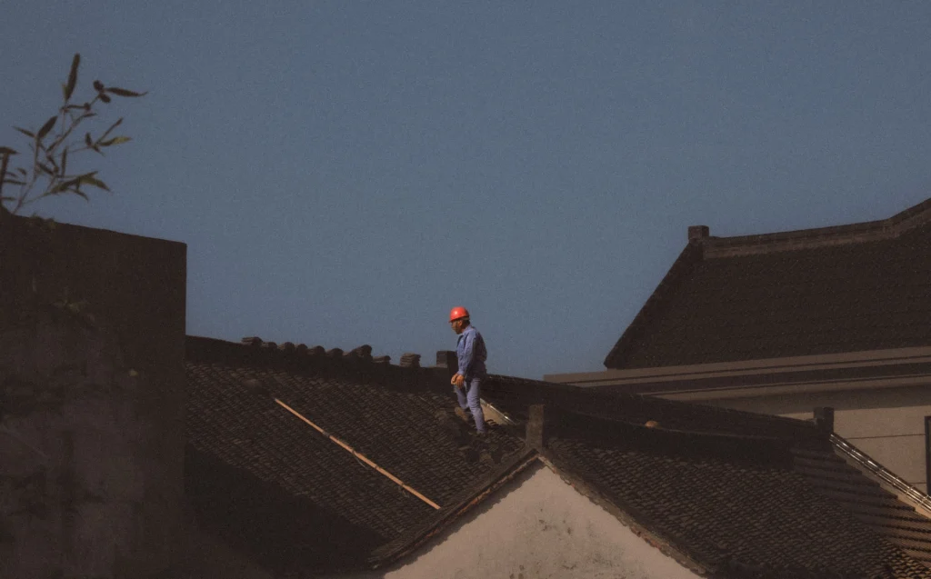 Roofing professional inspecting a tiled roof during wet weather as part of roof leak repairs in Victoria Park.